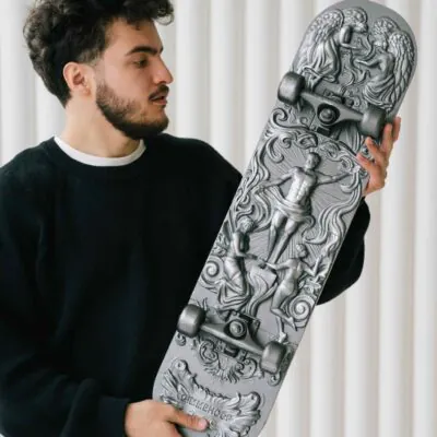 Sculptural silver skateboard held in a workshop